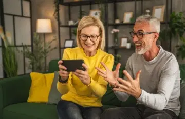 an elderly couple enjoying playing a game together on her phone