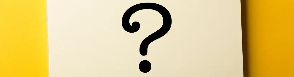 a black question mark on a pad of paper sitting on a yellow table