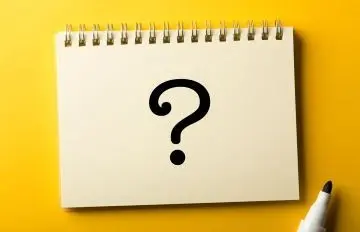 a black question mark on a pad of paper sitting on a yellow table