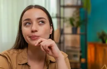 an attractive young woman thinking deeply about something. She is looking out but not focusing on anything.
