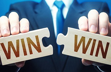 man in a suit holding two pieces of a puzzle. each piece says WIN. it shows how strategy helps people succeed.