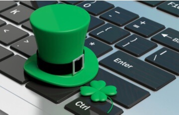 laptop keyboard with a leprechaun's hat and a four leaf clover sitting on it.