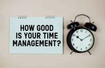 ring notebook with "how good is your time management" in large black letters with a black alarm clock next to the notebook 