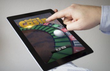 a roulette wheel on a tablet with the words Online Casino on the screen indicating the growth in mobile casinos
