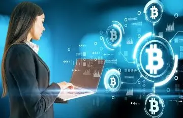 young businesswoman at a laptop board with space age symbols of bitcoin seemingly floating in air