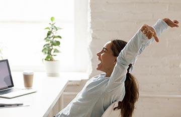 young woman at a desk ecstatic about receiving a bonus