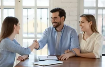 a smiling thirty-something couple receiving good advice from a woman advisor