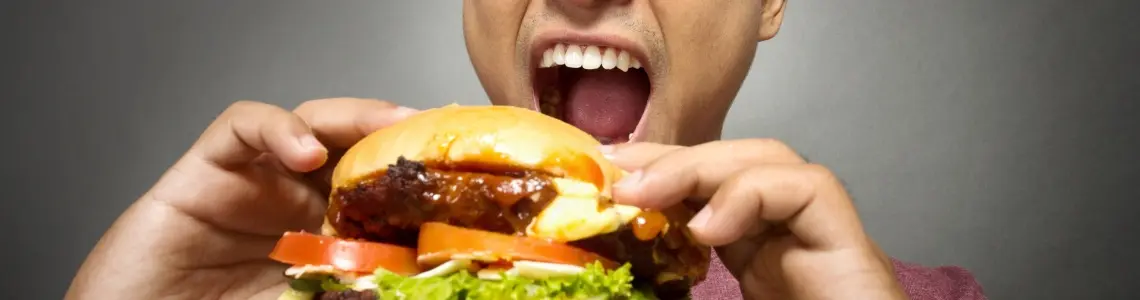 man anxiously eating a double burger with all the fixings