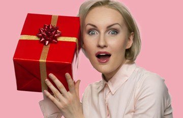 an attractive young woman in a white blouse holding a red box with a pink ribbon as a surprise bonus