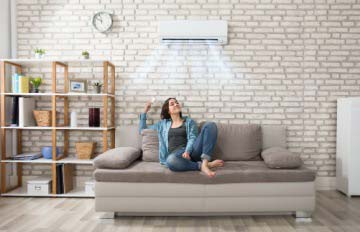 young woman lounging on soft comfortable sofa surrounded by conveniences such as a wall mounted air conditioner