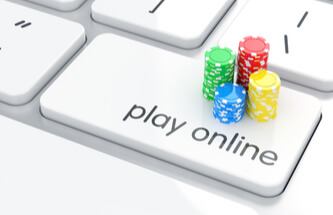 a laptop keyboard with Play Online written on a key and stacks of poker chips