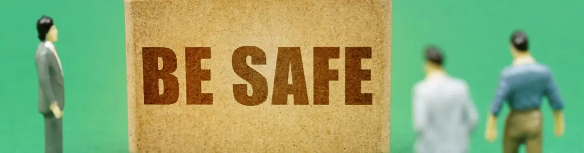 three toy figures of men standing and looking at a block of wood with the words BE SAFE on it