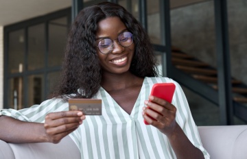 happy young woman with a credit card banking online. Her smile shows supreme confidence in the safety of online banking