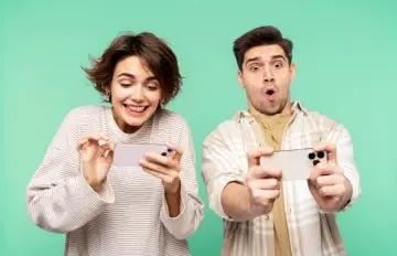 two young adults having fun playing on their phones