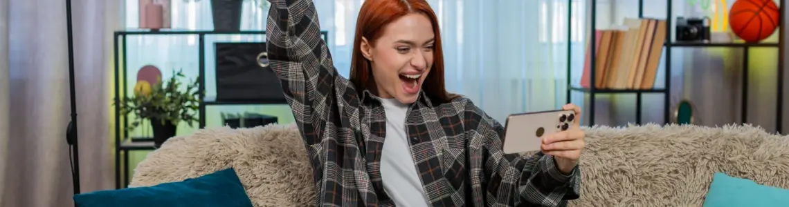 a young woman happy at a win playing on her phone