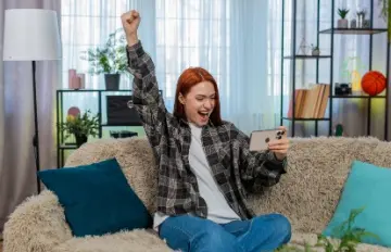 a young woman happy at a win playing on her phone