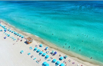 an overhead view of the beach and the sea at Miami Beach, Florida with a long line of beach umbrellas on the sand