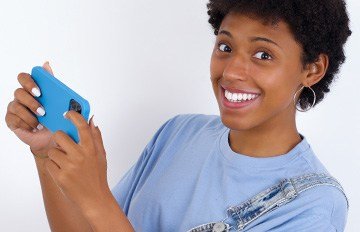 happy, attractive black young woman playing online casino games on her mobile device