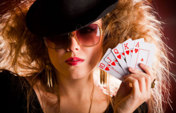pretty high class woman in her 20's with tinted sunglasses and stylish hat holding a Royal flush