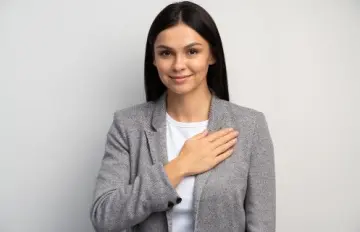 a smiling young woman holding her hand over her heart demonstarting her pledge to being responsible in her actions