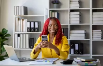 an attractive, smiling African-American businesswoman at work wearing a yellow suit showing how she can make work fun