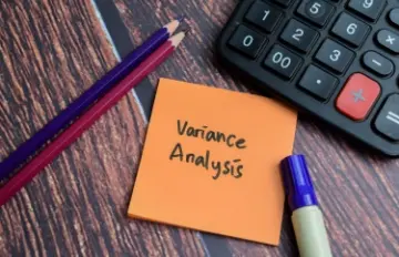 idea of variance shown by calculator on desk with two pencils and note pad with words variance analysis on it