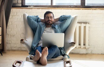 sleepy man with glasses in an armchair with the laptop in his lap