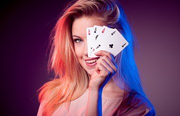an attractive young woman smiling because she just got four aces and she is showing them to us.