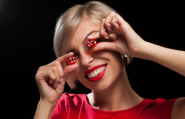 smiling very pretty young woman with a red dress and red lipstick holding red dice by her eyes 