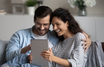 young couple happily enjoying online casino games on their tablet