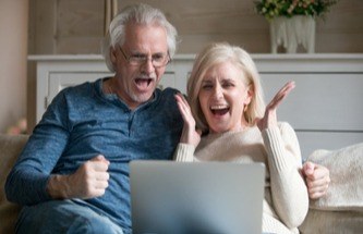 smiling gamers curled up to play slots on laptop